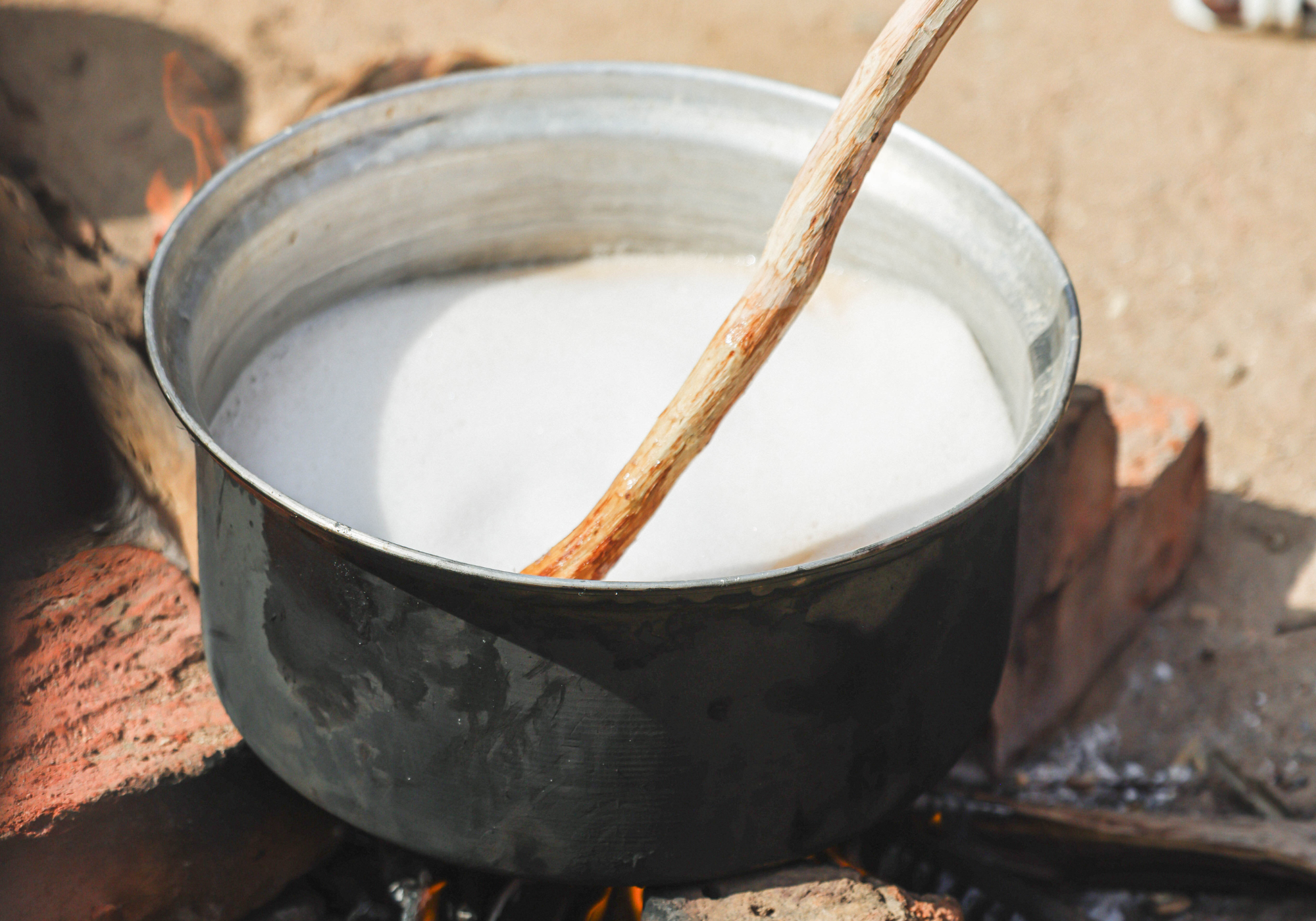 Metal pot with white liquid over a fire