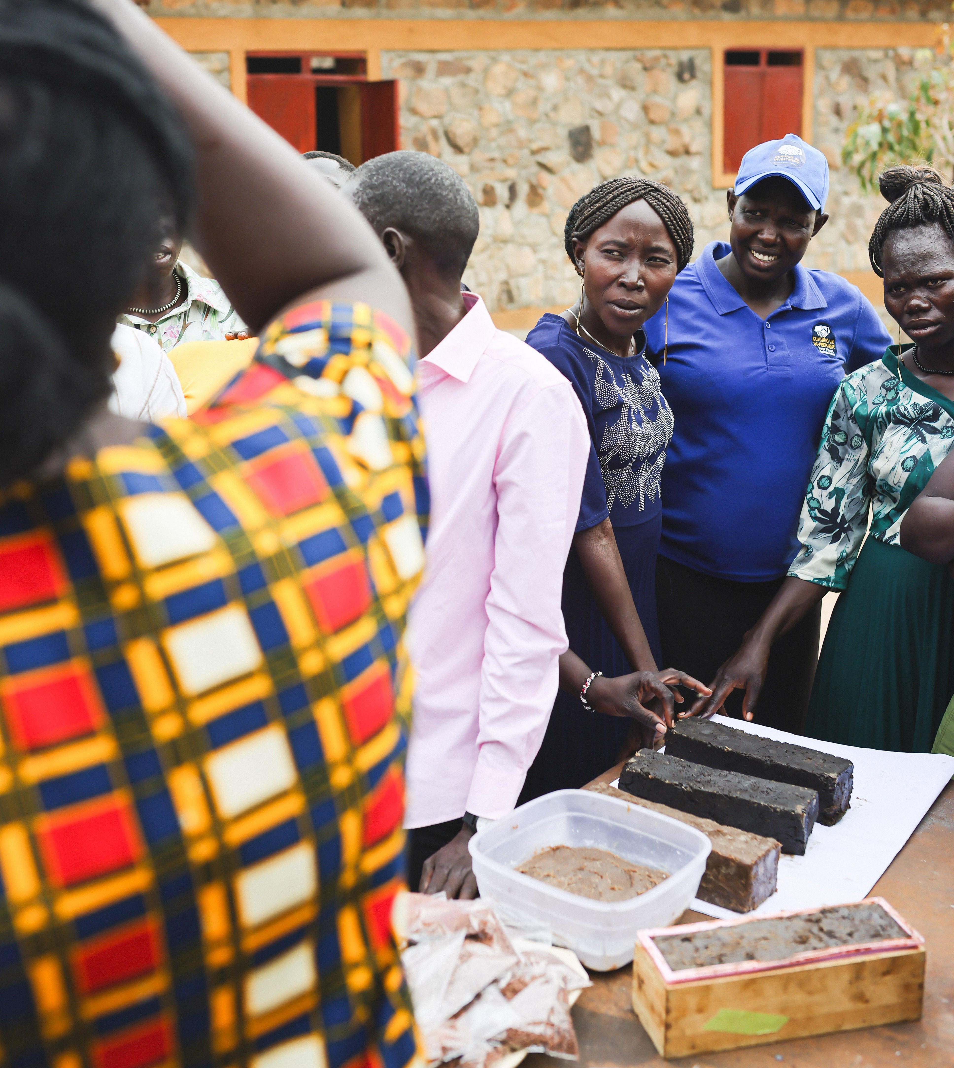 Group of people gathered around a table with food items in an outdoor setting.