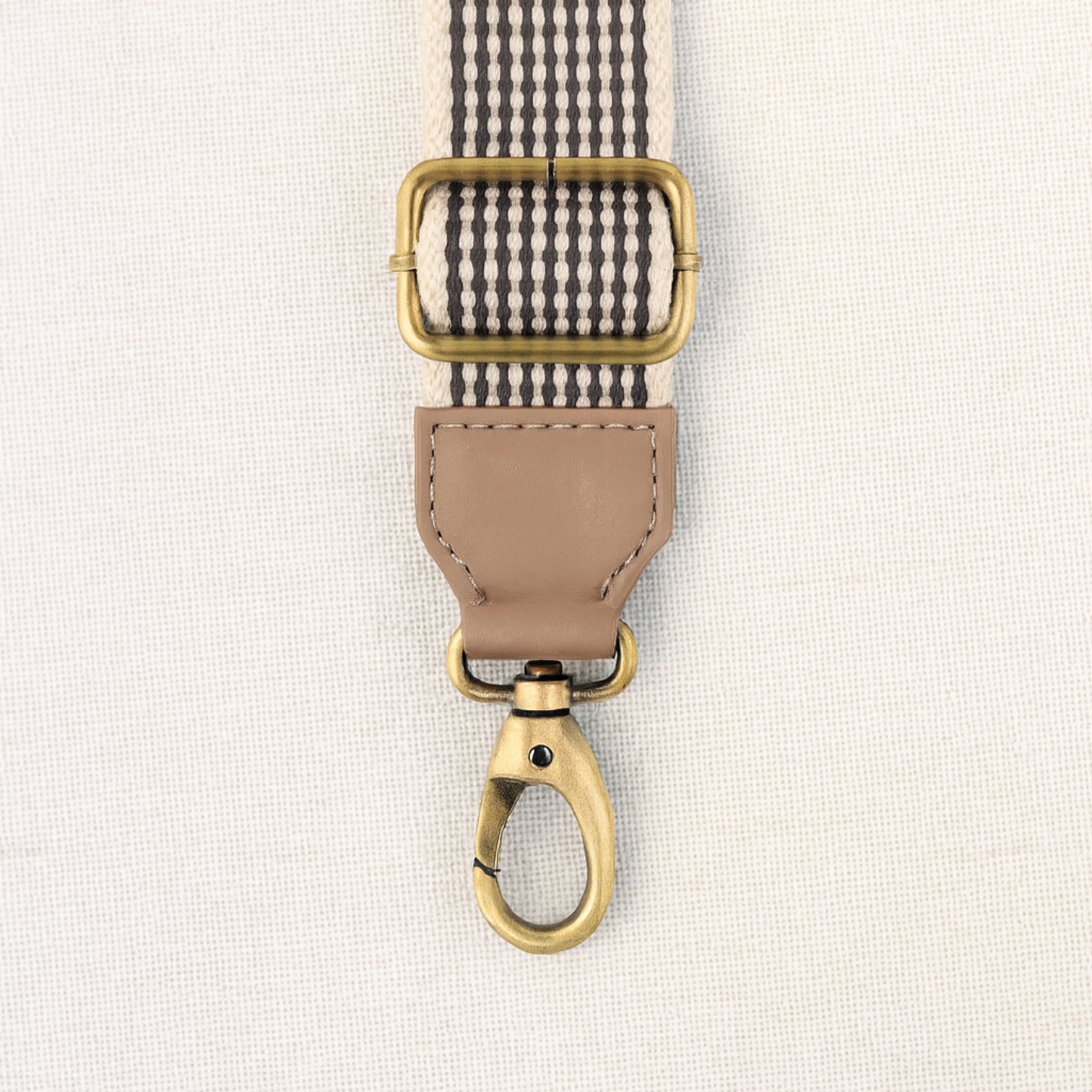Fabric strap with gold buckle and clasp on a light background
