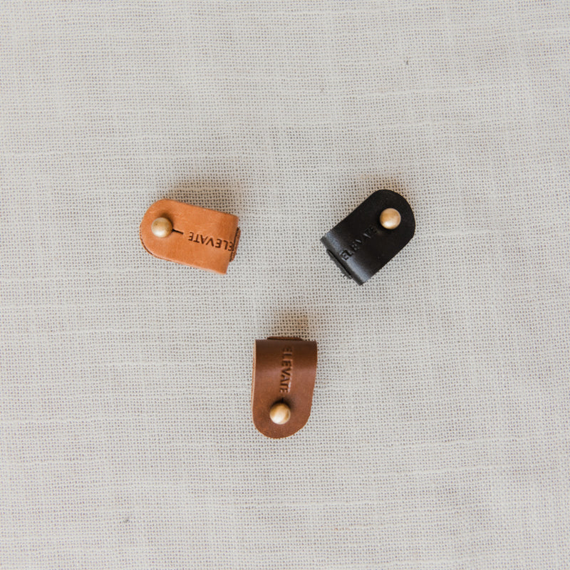 Portable Leather Cord Wrap Organizer in use, demonstrating elegant cable management for chargers and earphones.