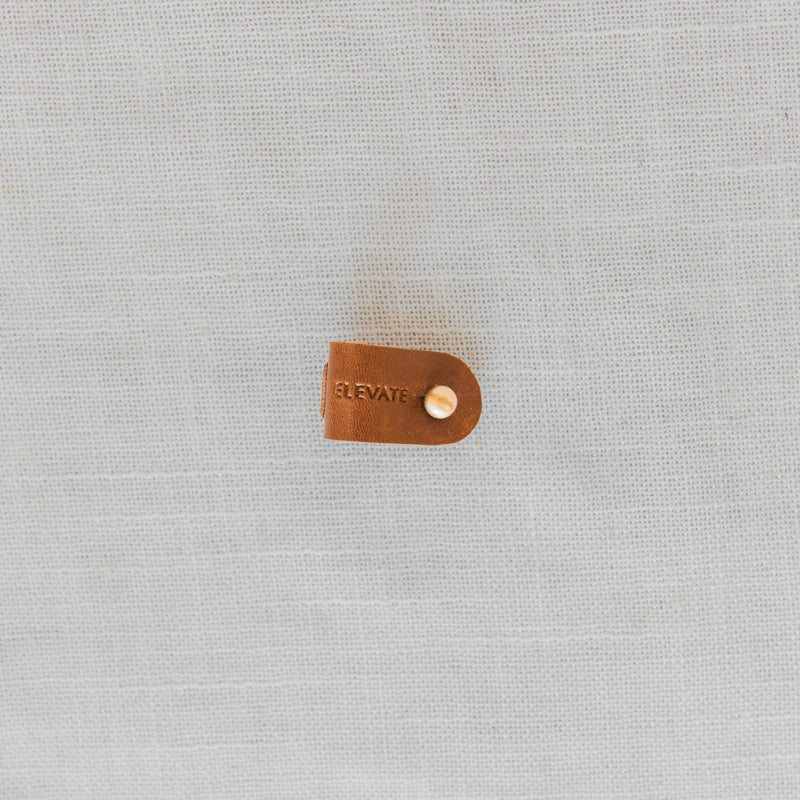 Gift-ready Leather Cord Wrap Organizer displayed with tech accessories, perfect for anyone seeking organized storage.