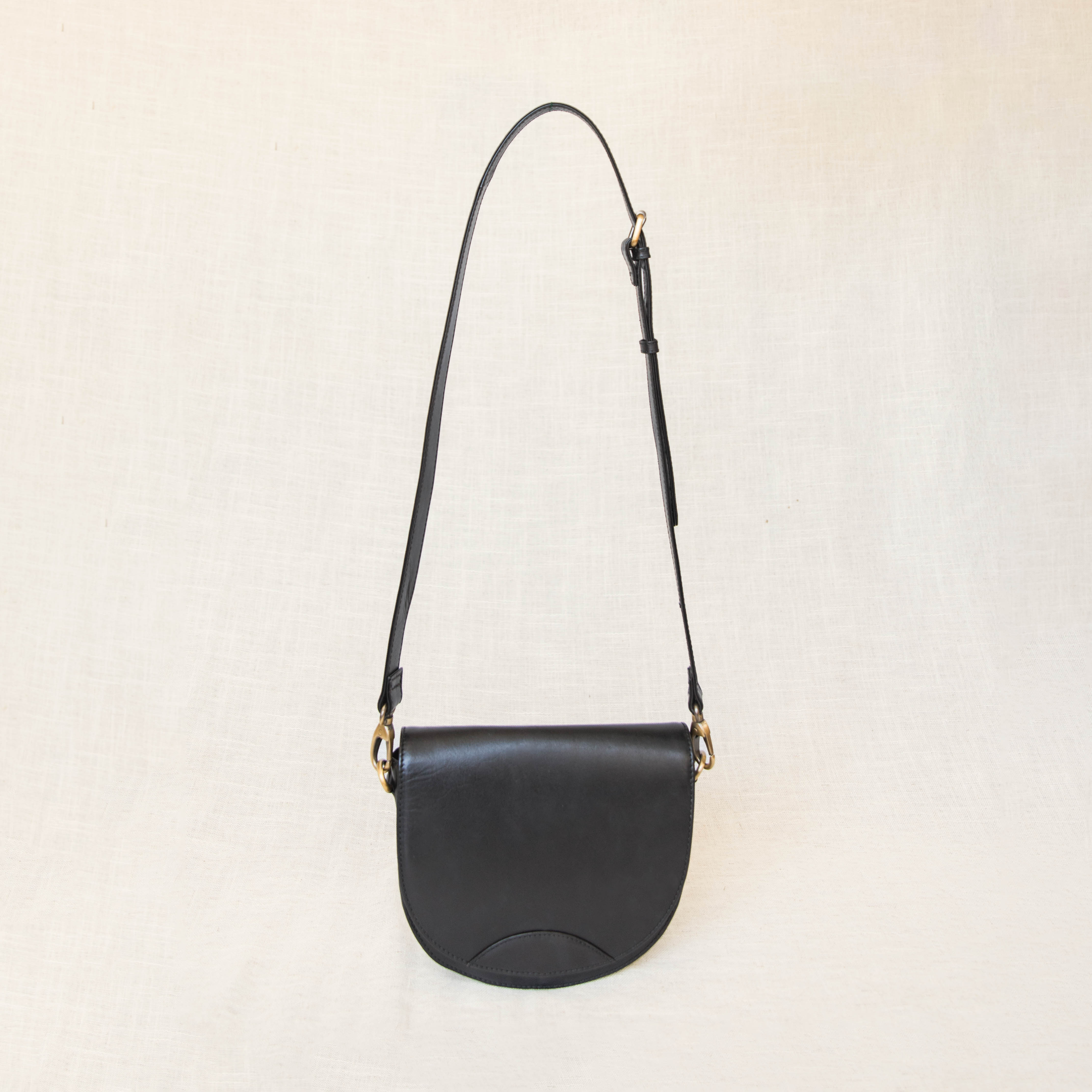 Close-up of the adjustable leather crossbody strap, demonstrating premium leather quality and antique brass hardware.