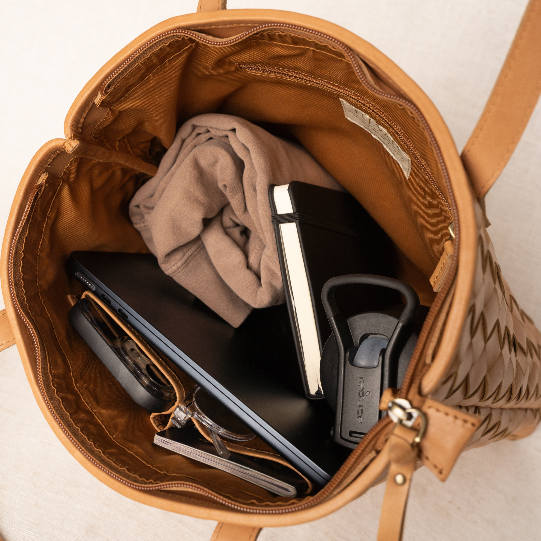 The interior of the Shirin Woven Leather Tote by Elevate, showing ample space for essentials like a laptop, clothing, and accessories.