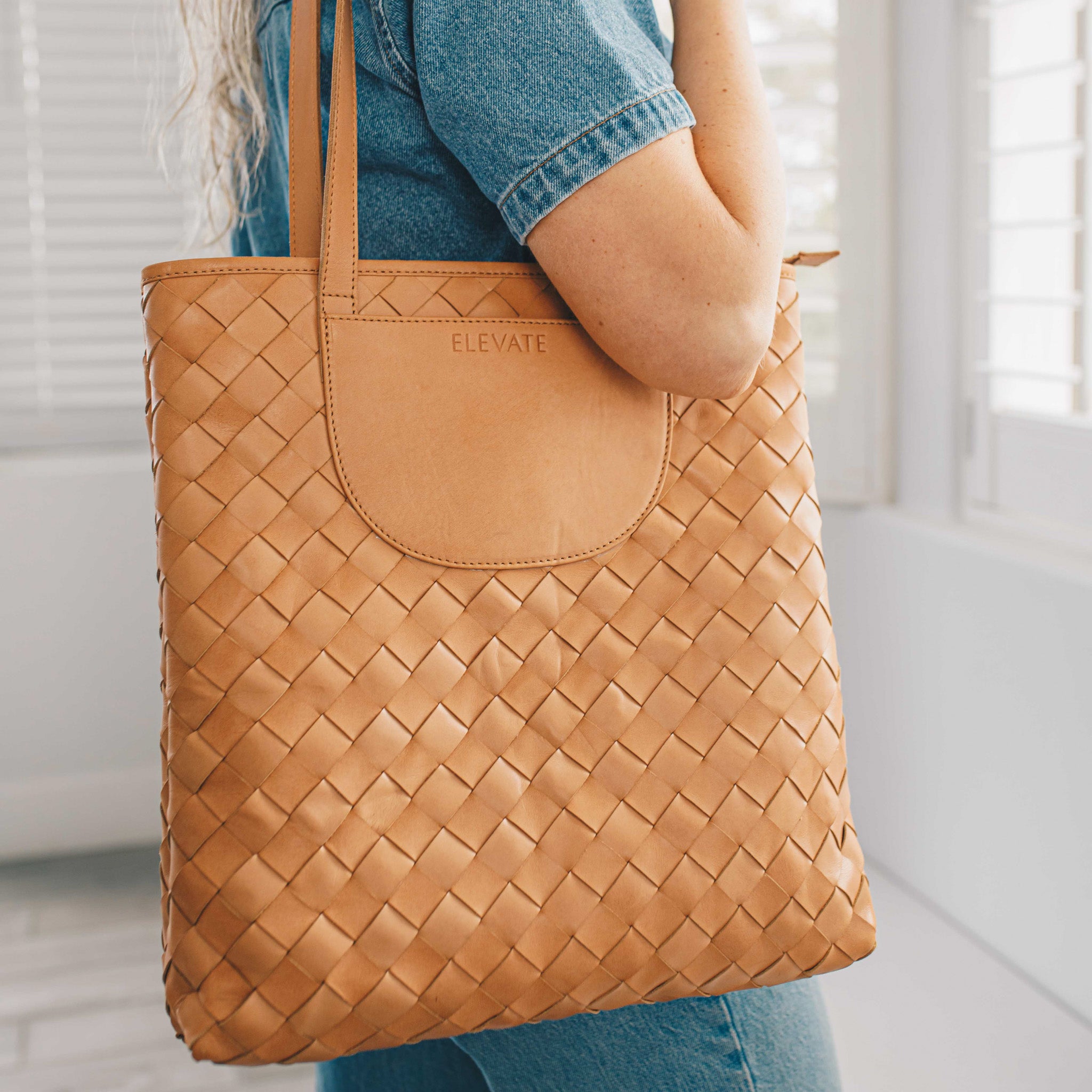 Close-up of a woman holding the Shirin Woven Leather Tote by Elevate, highlighting its handwoven texture and elegant style.