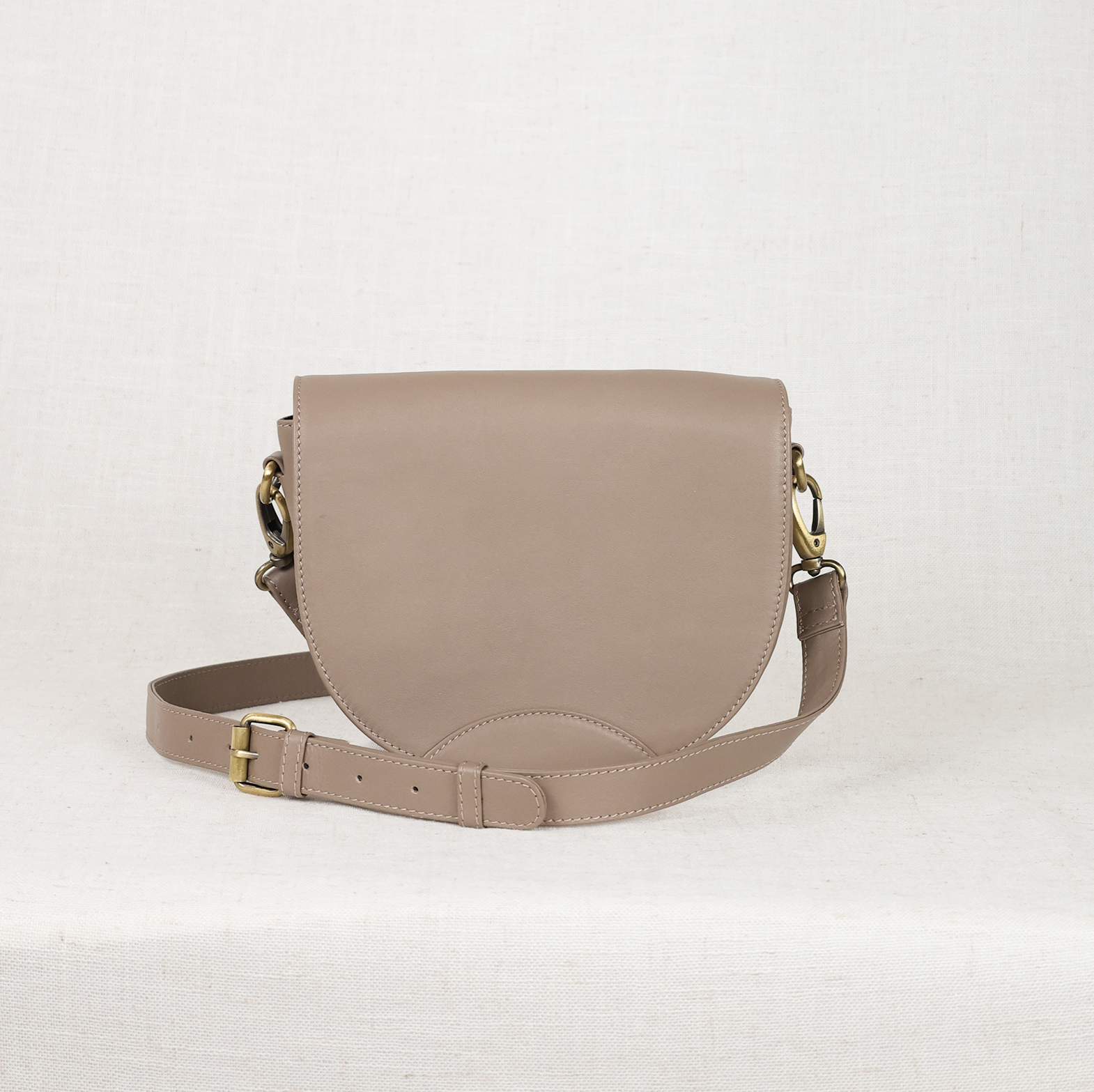 Taupe leather saddle bag on a white background