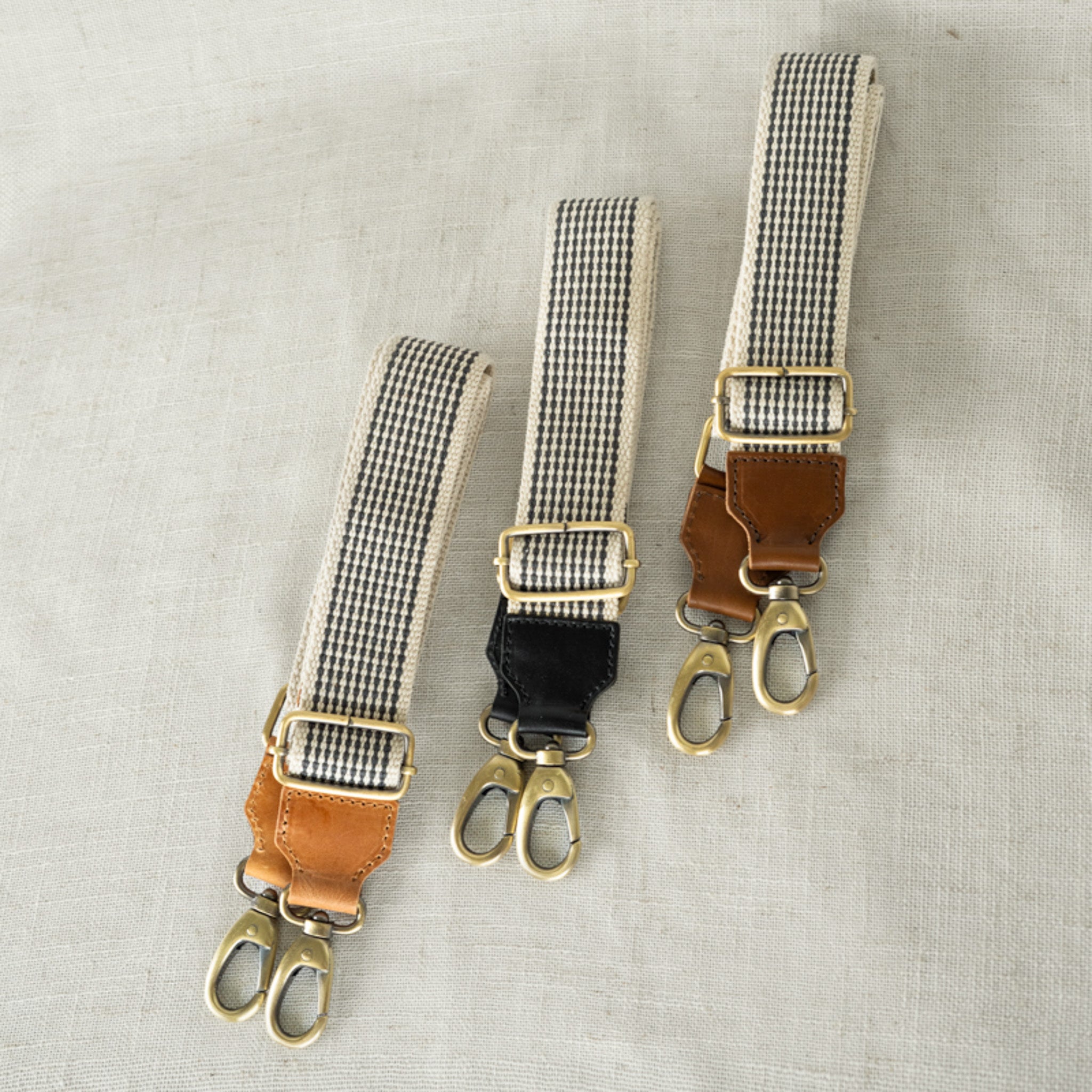 Various lengths of the Woven Crossbody Bag Strap by Elevate, featuring a stylish black-and-white pattern and leather accents, adjustable from 33" to 54".