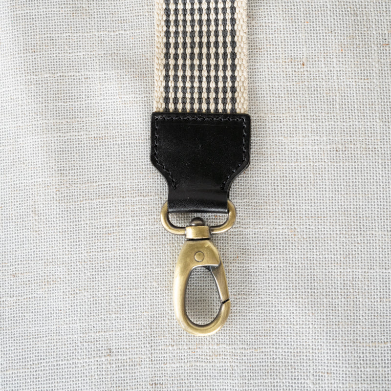 Close-up of the black leather accent on the Woven Crossbody Bag Strap by Elevate, highlighting its durable design and stylish detail.