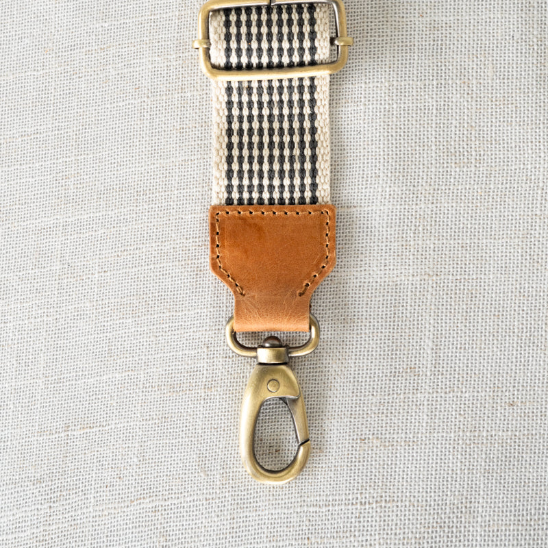 Close-up of the leather accent on the Woven Crossbody Bag Strap by Elevate, showing its quality craftsmanship and attachment clip.