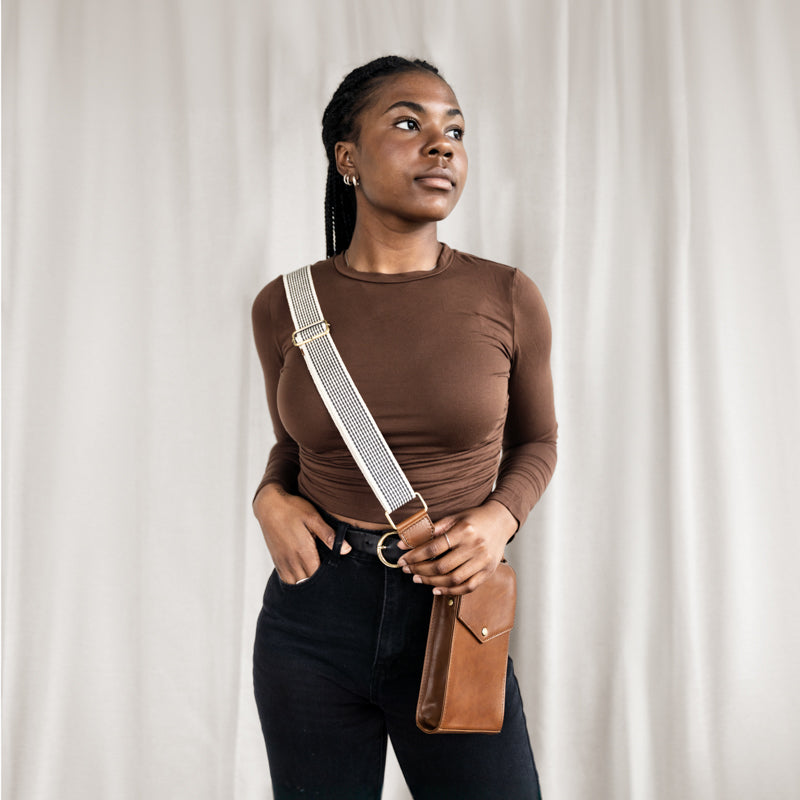 Woman modeling the Woven Crossbody Bag Strap by Elevate in a brown long-sleeve top, showcasing its adjustable feature with a leather bag.