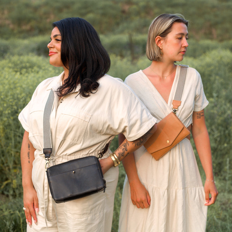 Two women posing outdoors wearing the Woven Crossbody Bag Strap by Elevate, showcasing different styles and bags while emphasizing its versatility.
