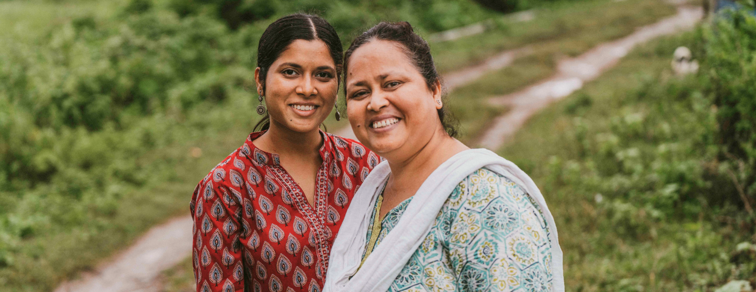 two women standing on a path in india smiling