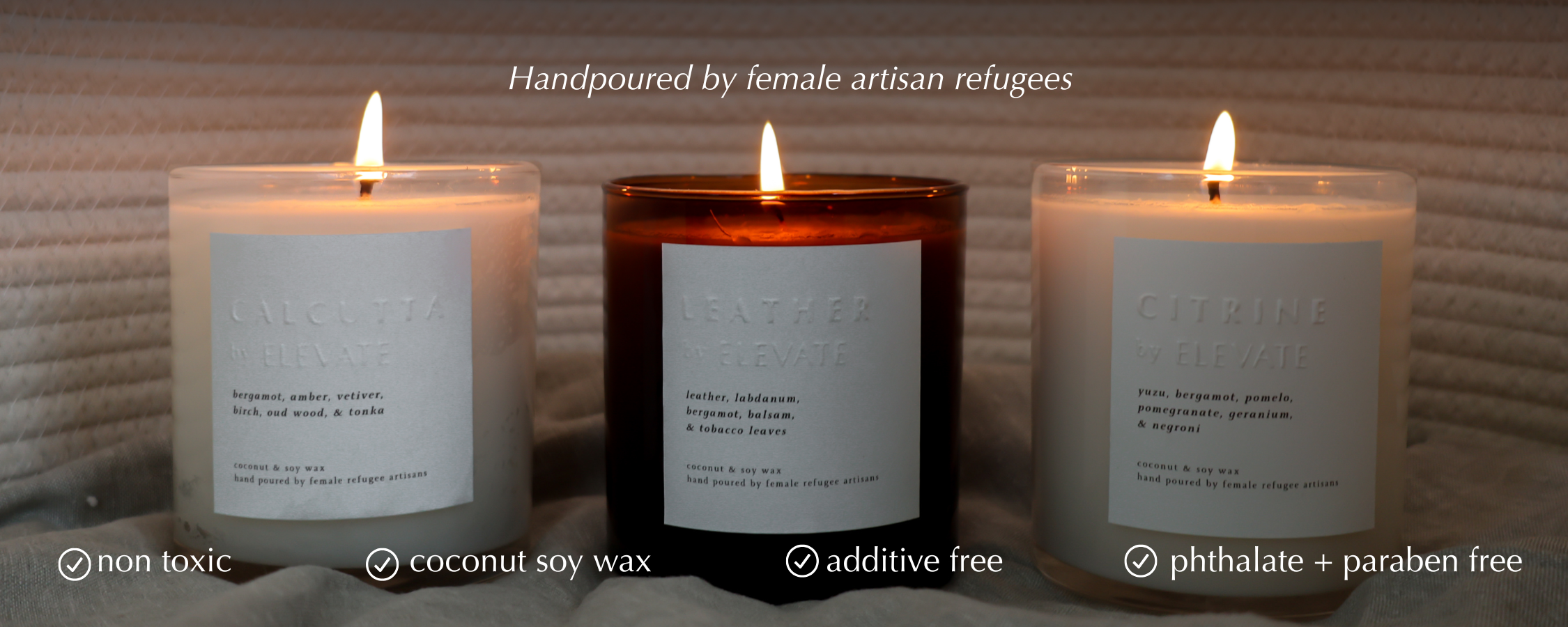 Three lit candles with labels on a textured surface, featuring text about product details.