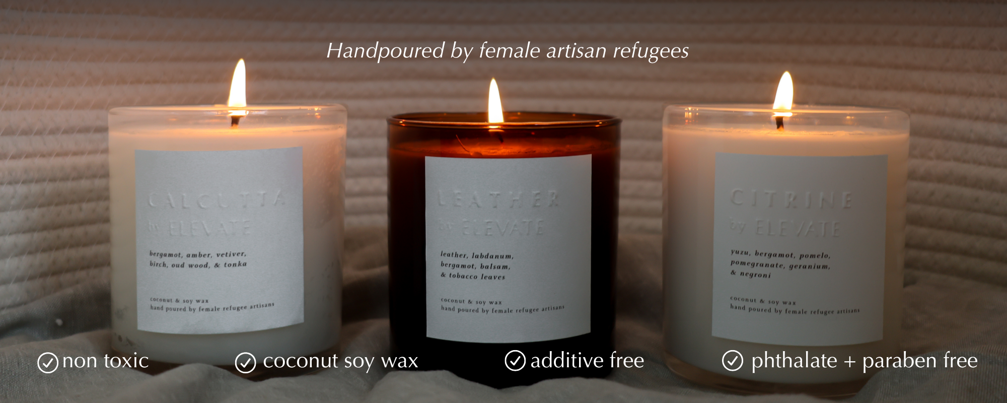 Three lit candles with labels on a textured surface, featuring text about the candle's origin and properties.