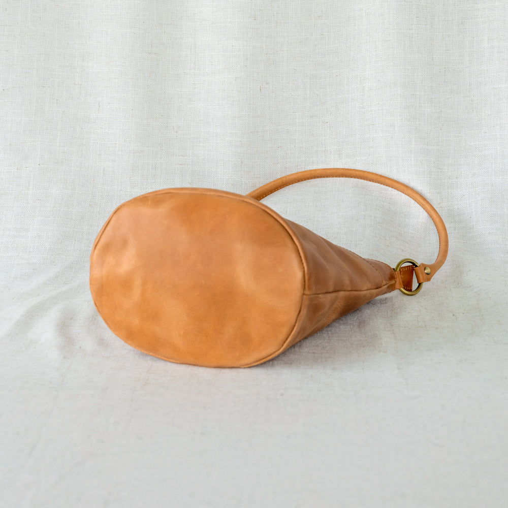 The Newport Tote with a woven crossbody strap, enhancing its versatility as an elegant leather bucket tote bag.