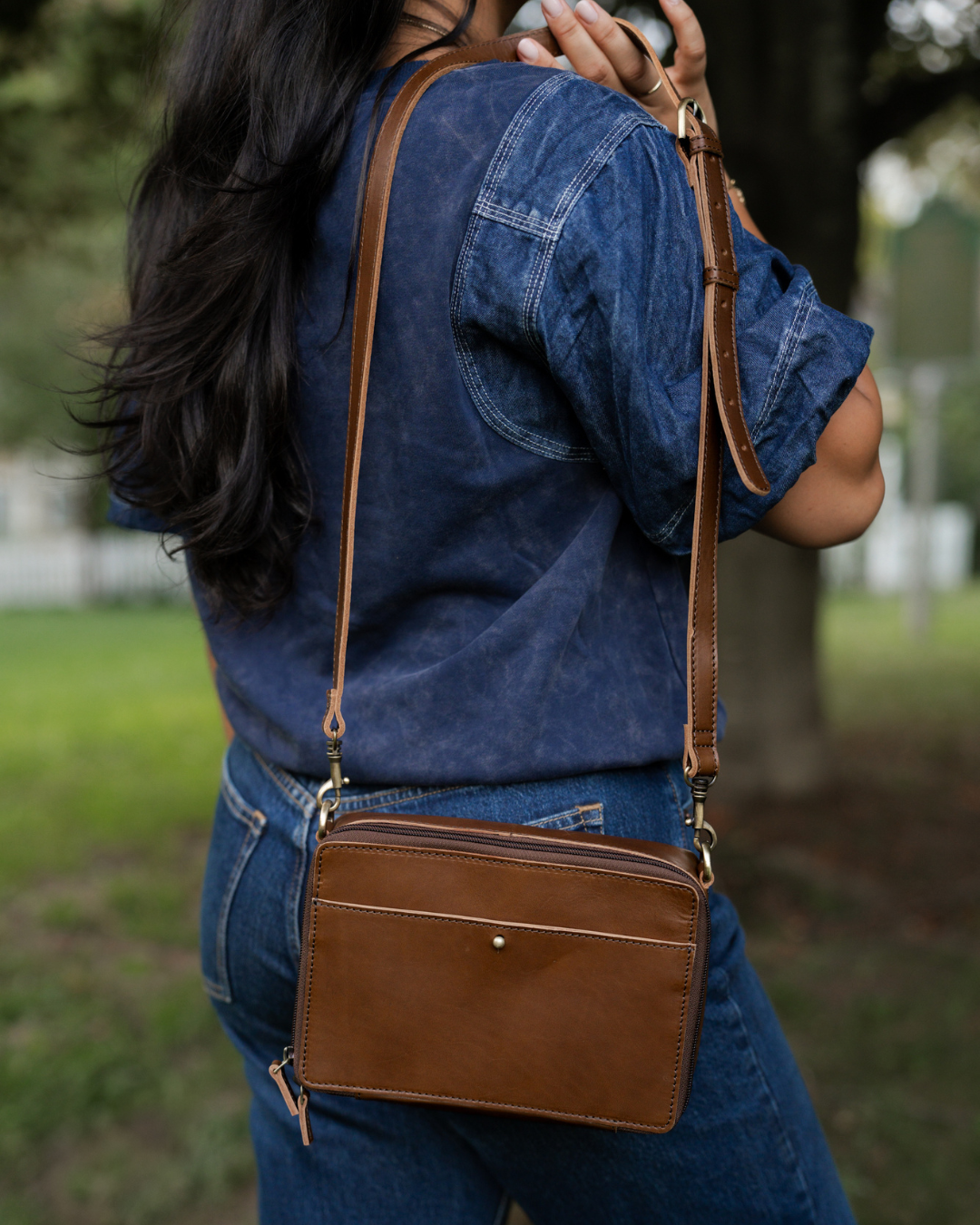 Person wearing a brown leather crossbody bag outdoors