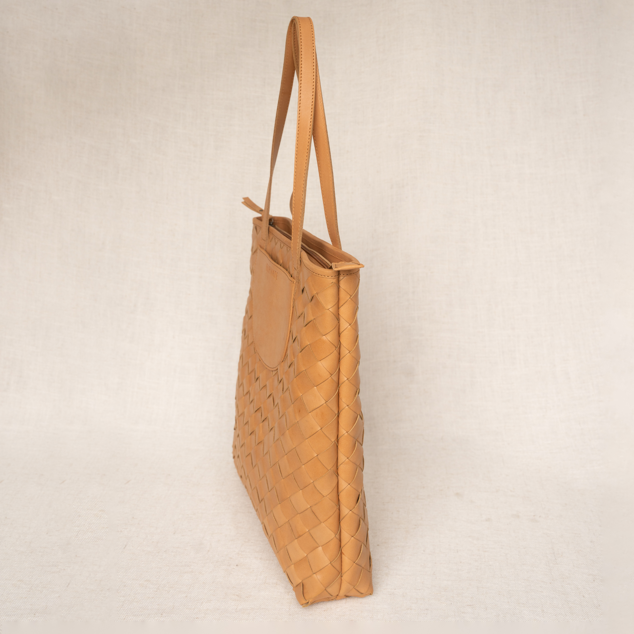 A side profile of the Shirin Woven Leather Tote by Elevate, emphasizing its sleek design and woven leather craftsmanship.