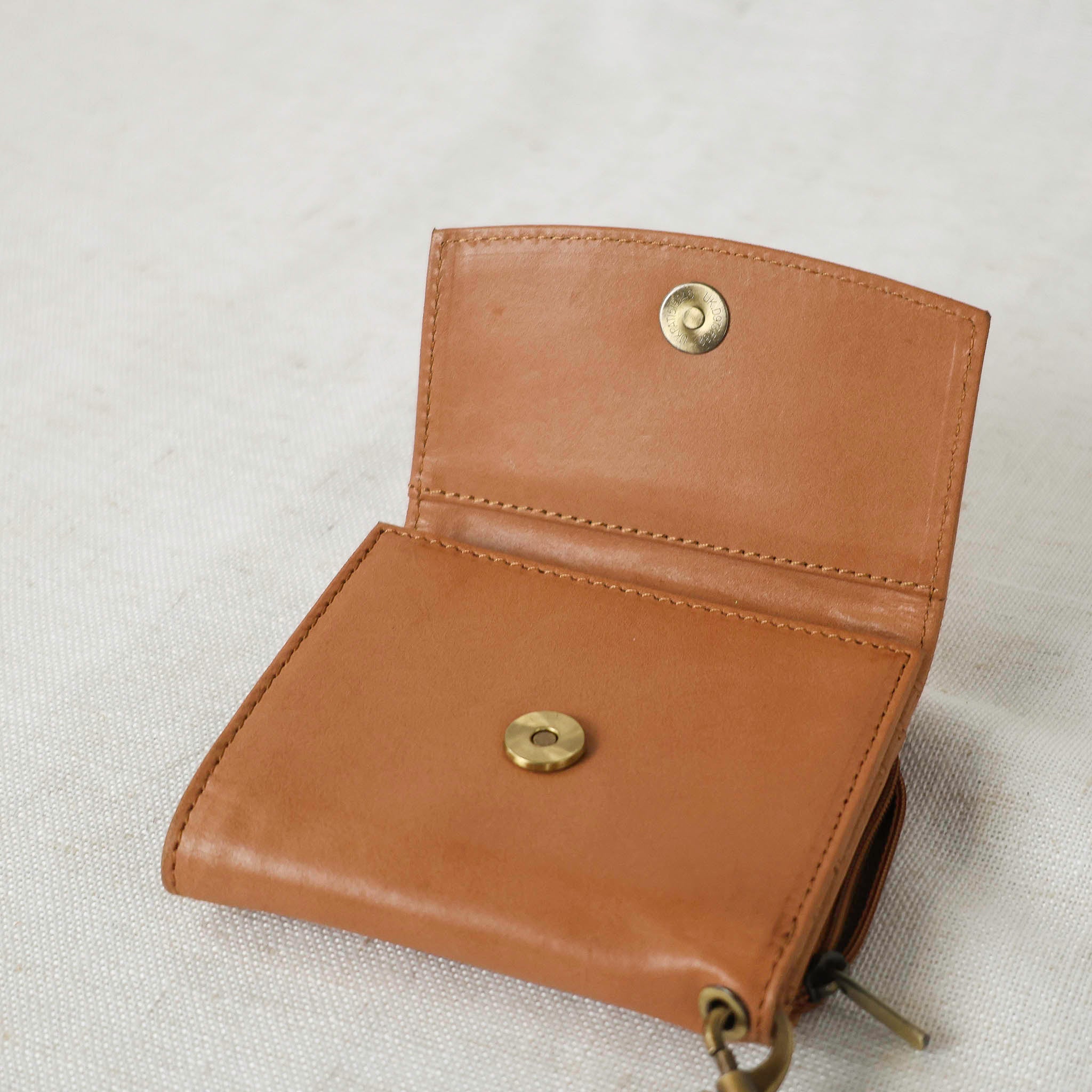 Lifestyle shot of a woman using Suri Wallet in a coffee shop, highlighting its practicality as a leather wallet for women.