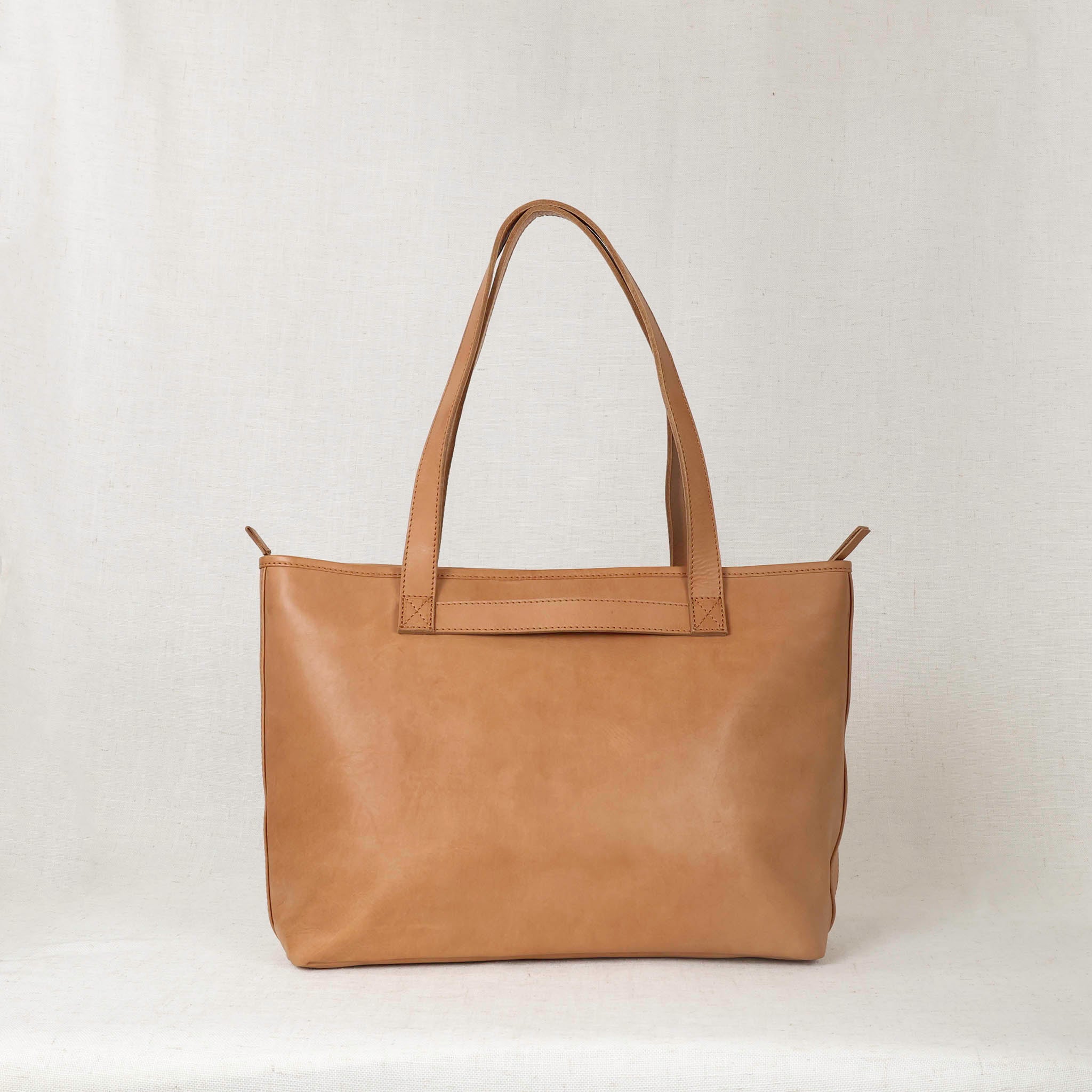 The functional trolley strap on the Tara Tote - Premium Leather Tote With Laptop Sleeve for easy travel.