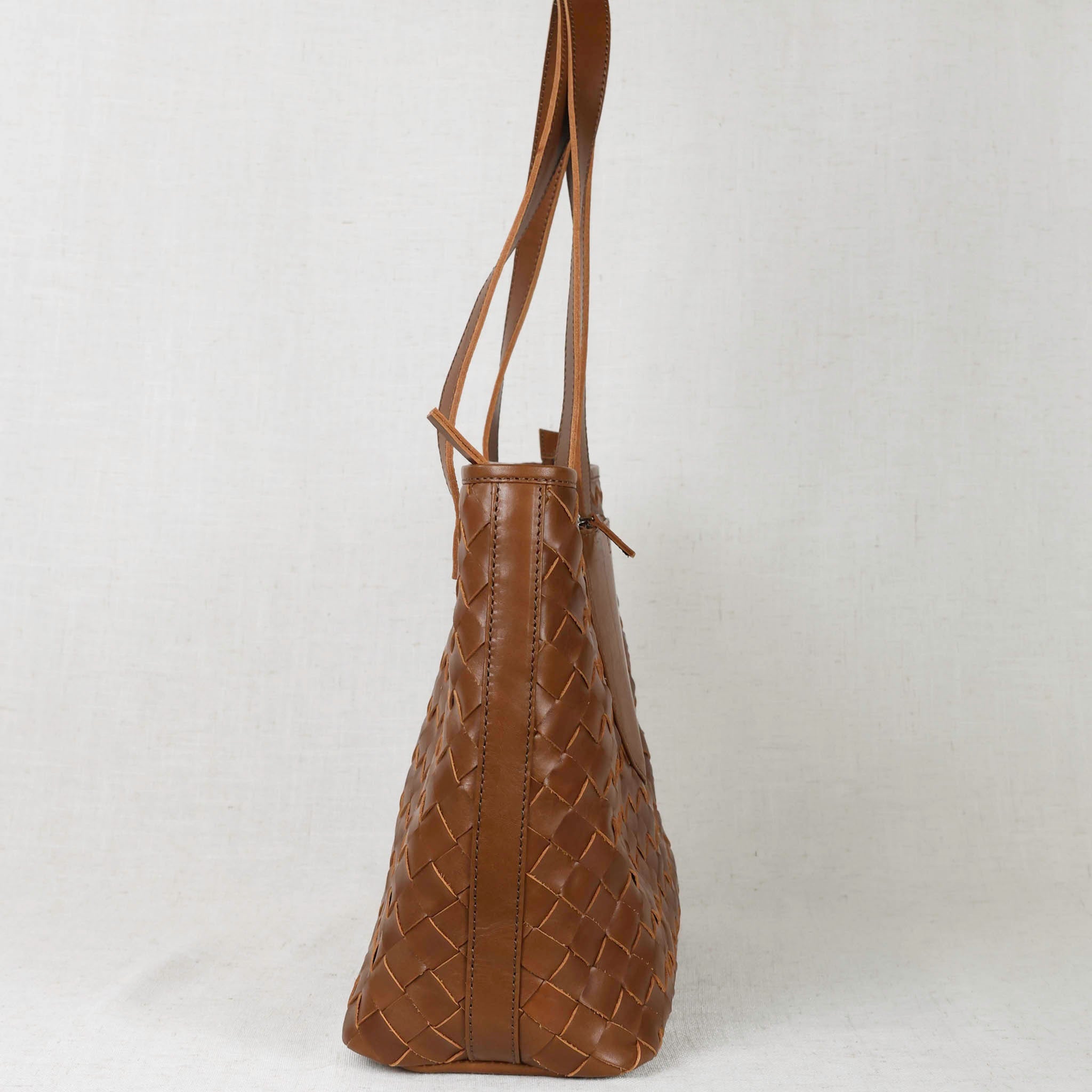Woven Tara Tote – Hand Woven Leather Tote displayed with trolley strap, ideal for travel and stylish organization.