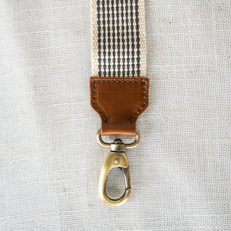 Close-up of the tan leather accent on the Woven Crossbody Bag Strap by Elevate, showcasing the quality materials and craftsmanship.