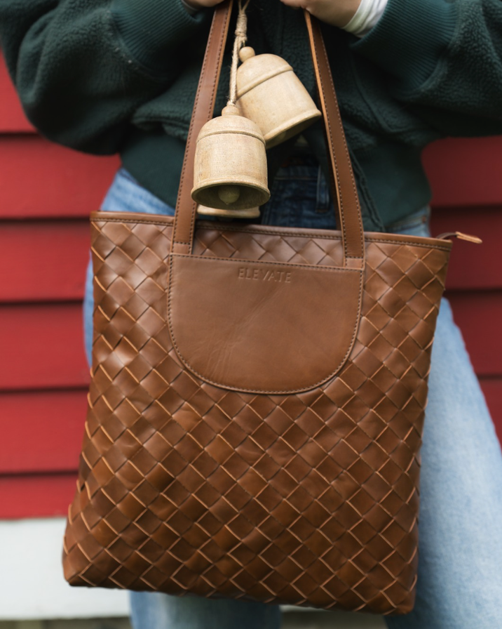 Brown woven handbag held by a person with a red background