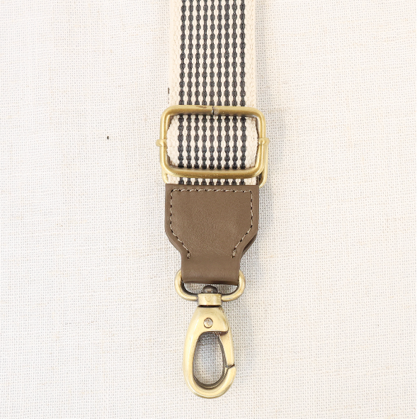 Fabric strap with gold buckle and clasp on a beige background